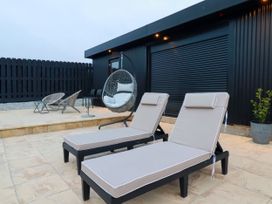 Outdoor seating area with lounge chairs and a hanging chair at The Lake Boat exclusive retreat Black Cross near St Columb Major
