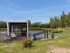 A floating house by water with a deck and charging station at The Lake Boat exclusive retreat Black Cross near St Columb Major