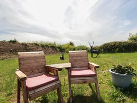 Two wooden chairs and a table in a garden at The Lake Boat exclusive retreat Black Cross near St Columb Major