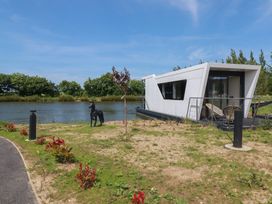 A houseboat by the water with a statue and plants at The Lake Boat exclusive retreat Black Cross near St Columb Major