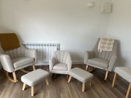 A living room with furniture including armchairs and footstools at The Lake Boat exclusive retreat Black Cross near St Columb Major