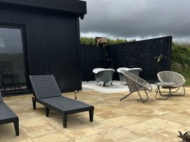 An outdoor area with bathtubs, deck chairs, and woven chairs at The Lake Boat exclusive retreat Black Cross near St Columb Major