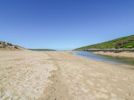 A beach with a river flowing and hills in the background at Byron’s Retreat in Crantock
