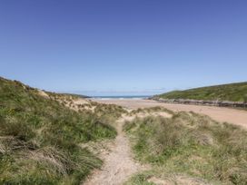 A pathway leading to a beach with grass and sand at Byron’s Retreat in Crantock