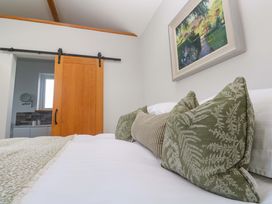 A bedroom with pillows on a bed and a sliding door at Byron’s Retreat in Crantock
