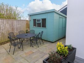 A garden with a table and chairs next to a shed at Byron’s Retreat in Crantock