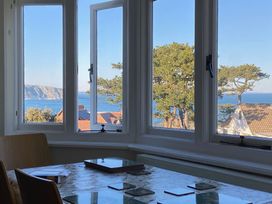 A dining room with a view of the sea and coast at Purbeck Vista in Swanage
