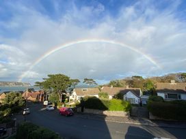 An outdoor view with a rainbow over houses and a road at Purbeck Vista in Swanage