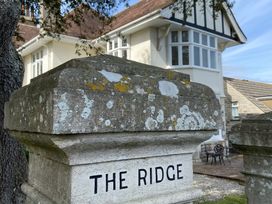 A house labeled The Ridge with a stone sign in front at Purbeck Vista Swanage