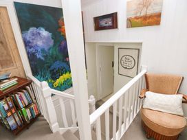 A staircase with paintings and a bookshelf at The Pink House in Nine Wells near Solva