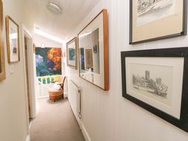 A hallway with paintings and a chair at The Pink House in Nine Wells near Solva