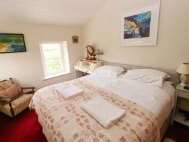 A bedroom with a bed and artwork on the wall at The Pink House in Nine Wells near Solva