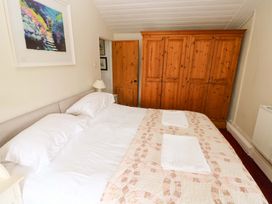 A bedroom with a bed and wardrobe at The Pink House Nine Wells near Solva