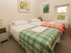 A bedroom with two beds, a lamp, and paintings at The Pink House in Nine Wells near Solva