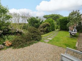 A garden with a pathway and hammock at The Pink House in Nine Wells near Solva