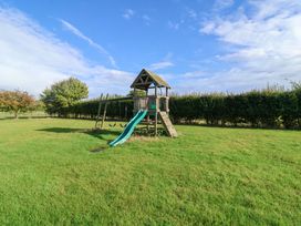 A playground with a slide and swing in a grassy area at Churn House Ipswich