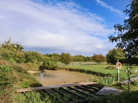 A riverbank scene with grass and benches at Churn House in Ipswich