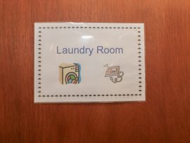 A sign indicating Laundry Room with icons at Wheelwright's Cottage in Ipswich