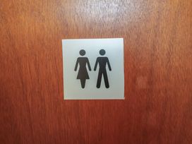 A restroom sign with male and female icons at Wheelwright's Cottage, Ipswich