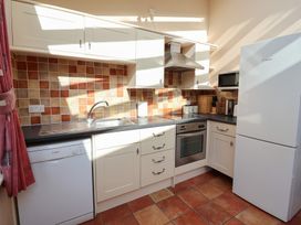 A kitchen with a sink, dishwasher, oven, and refrigerator at Wheelwright's Cottage in Ipswich