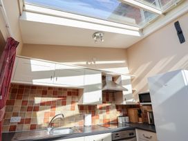 A kitchen with cabinets and appliances at Wheelwright's Cottage in Ipswich