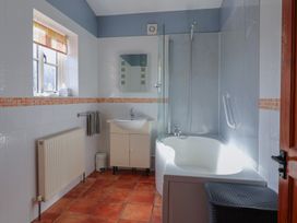 A bathroom with a bath tub, sink, and shower at Wheelwright's Cottage in Ipswich