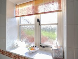 A bathroom window with shampoo bottles and toiletries at Wheelwright's Cottage in Ipswich
