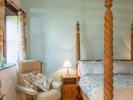 A bedroom with a bed and an armchair at Billy's Barn in Bradworthy