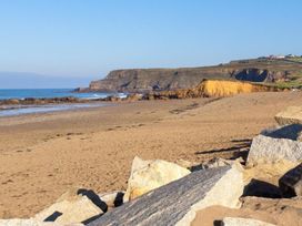 A beach with sand, ocean waves and cliffs at Billy's Barn in Bradworthy