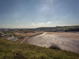 A beach view with sand and water and beach huts at Billy's Barn in Bradworthy