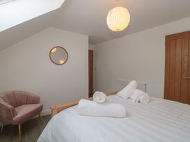 A bedroom with a bed, chair, and mirror at 3 The Stables in Highbridge