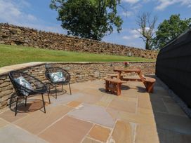 An outdoor seating area with a wooden table and stone wall at Barley near Nelson