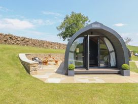 A glamping pod with a seating area and stone wall at Black Moss in Nelson
