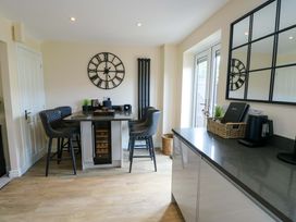 A kitchen with a table and bar stools at 20 Cysgod Y Bryn Rhos-On-Sea