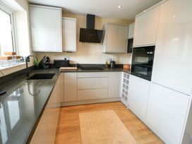 A kitchen with a sink, countertops, cabinets, and appliances at 20 Cysgod Y Bryn, Rhos-On-Sea