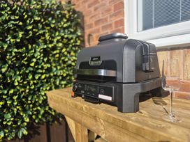 A barbecue grill on a wooden table in a garden at Hafan Rhos in Rhos-On-Sea