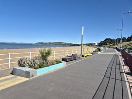 A beach promenade with benches and planters at Hafan Rhos in Rhos-On-Sea