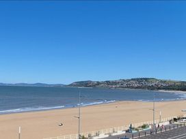 A beach scene with sand and water at Hafan Rhos in Rhos-On-Sea
