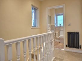 A landing with a staircase and a view into a bathroom at Hafan Rhos in Rhos-On-Sea