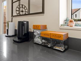 A kitchen countertop with kettle and storage containers at Hafan Rhos in Rhos-On-Sea