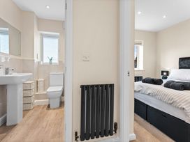 A bathroom with a sink and toilet next to a bedroom at Hafan Rhos in Rhos-On-Sea