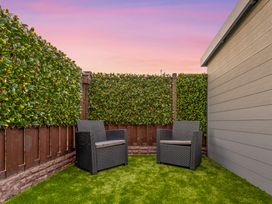 A garden with two chairs and green grass at Hafan Rhos in Rhos-On-Sea
