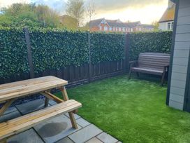 A garden with a table and bench at Hafan Rhos in Rhos-On-Sea