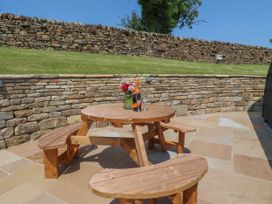 An outdoor patio with a wooden table and benches at Ogden in Nelson