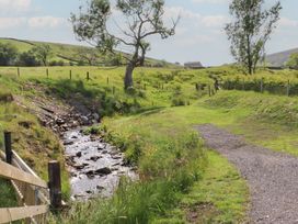 A stream alongside a path with trees and a fence at Pendle in Nelson