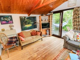 A living room with a sofa, armchair, and TV at The Tree House in Nine Wells near Solva