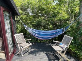 An outdoor space with a hammock and two wooden chairs at The Tree House in Nine Wells near Solva