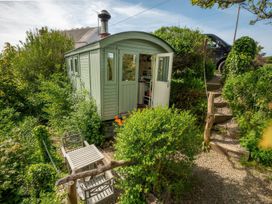 A hut surrounded by greenery with steps leading to a driveway at The Shepherd Hut near Nine Wells near Solva