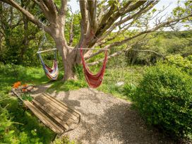 An outdoor area with two hammocks and a bench at The Shepherd Hut in Nine Wells near Solva