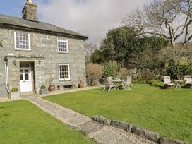 A garden with a house, chairs and a table at Bwthyn Morse in Llanfair